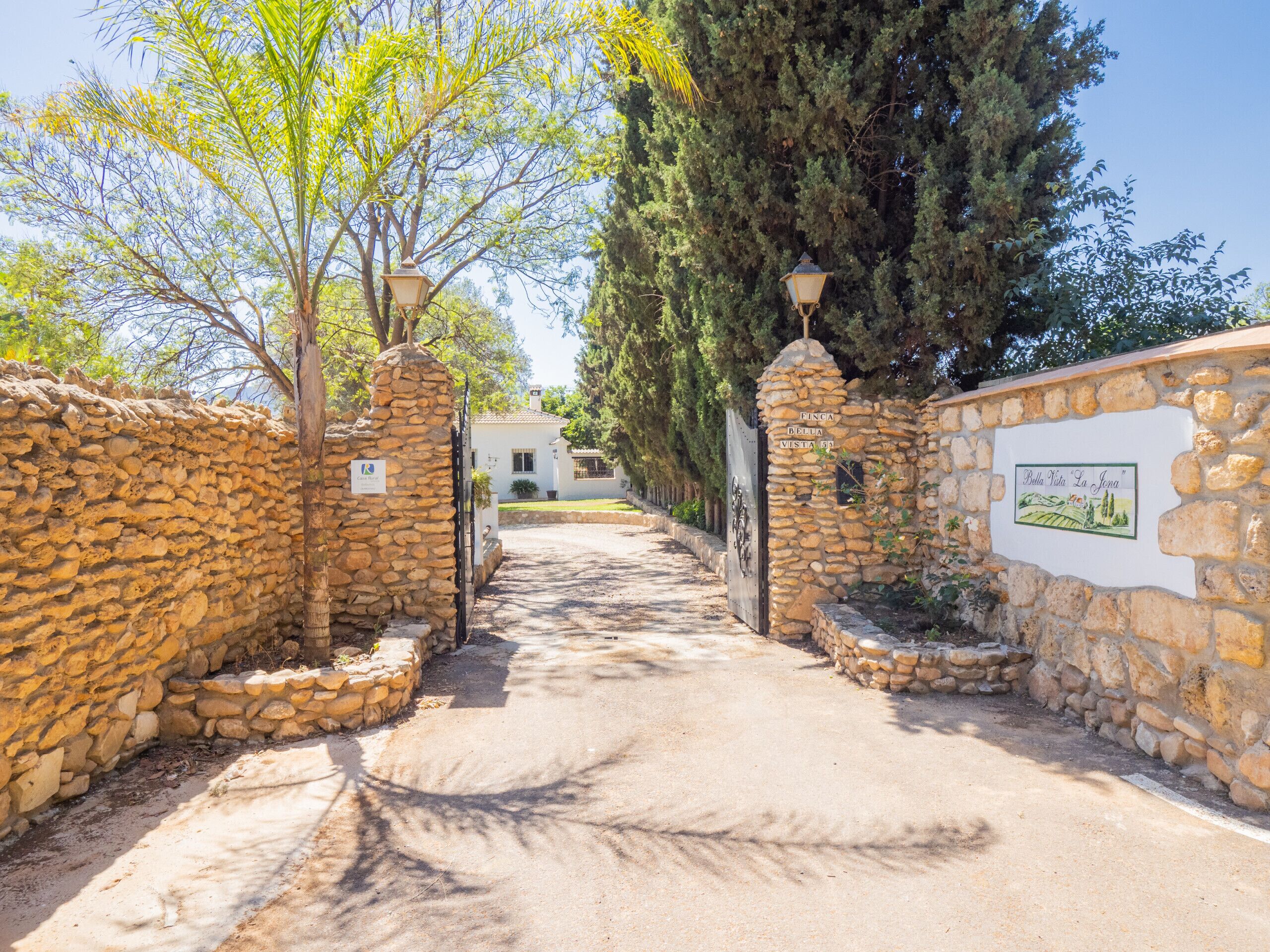 Un chemin de pierres mène à un bâtiment blanc sur lequel est apposée une enseigne indiquant « Finca Bella Vista ».