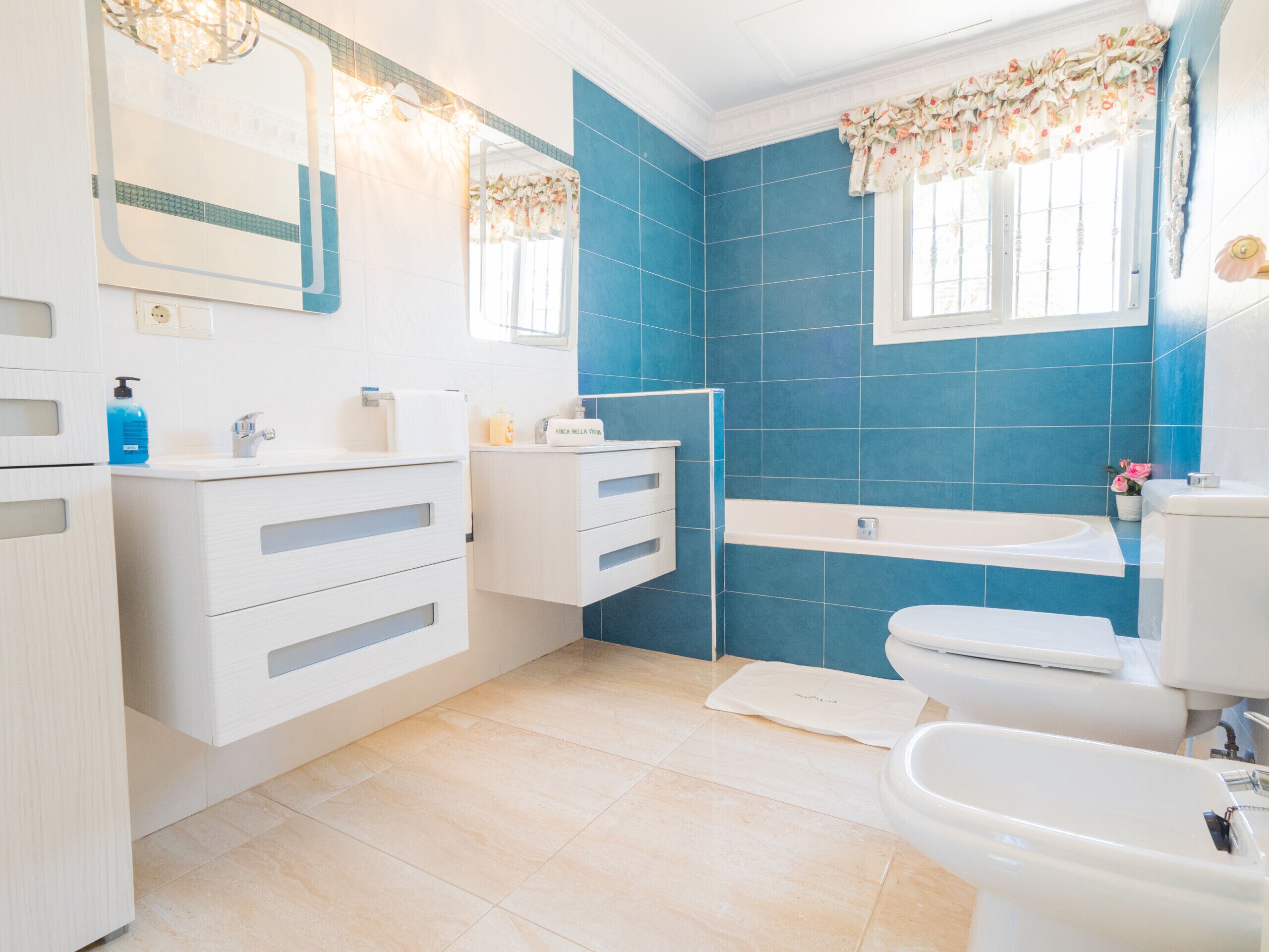 Ein modernes Badezimmer mit blauen Fliesen, einem weißen Waschbecken, einer Toilette und einer Duschkabine.