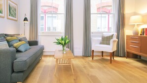Un salon moderne avec un canapé gris, un fauteuil blanc, une table basse en bois et un buffet.
