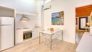 Een moderne keuken met witte kastjes, een inbouwoven en een eethoek met een glazen tafel en stoelen.