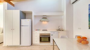 Een praktische keuken met witte kasten, een inbouwoven, een vaatwasser en een kleine eethoek met een tafel en stoelen.