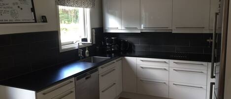 A kitchen with white cabinets, a black countertop, a coffee maker, and a dishwasher.