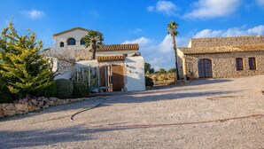A traditional stone building with a tiled roof, a small wooden door, and a gravel driveway.