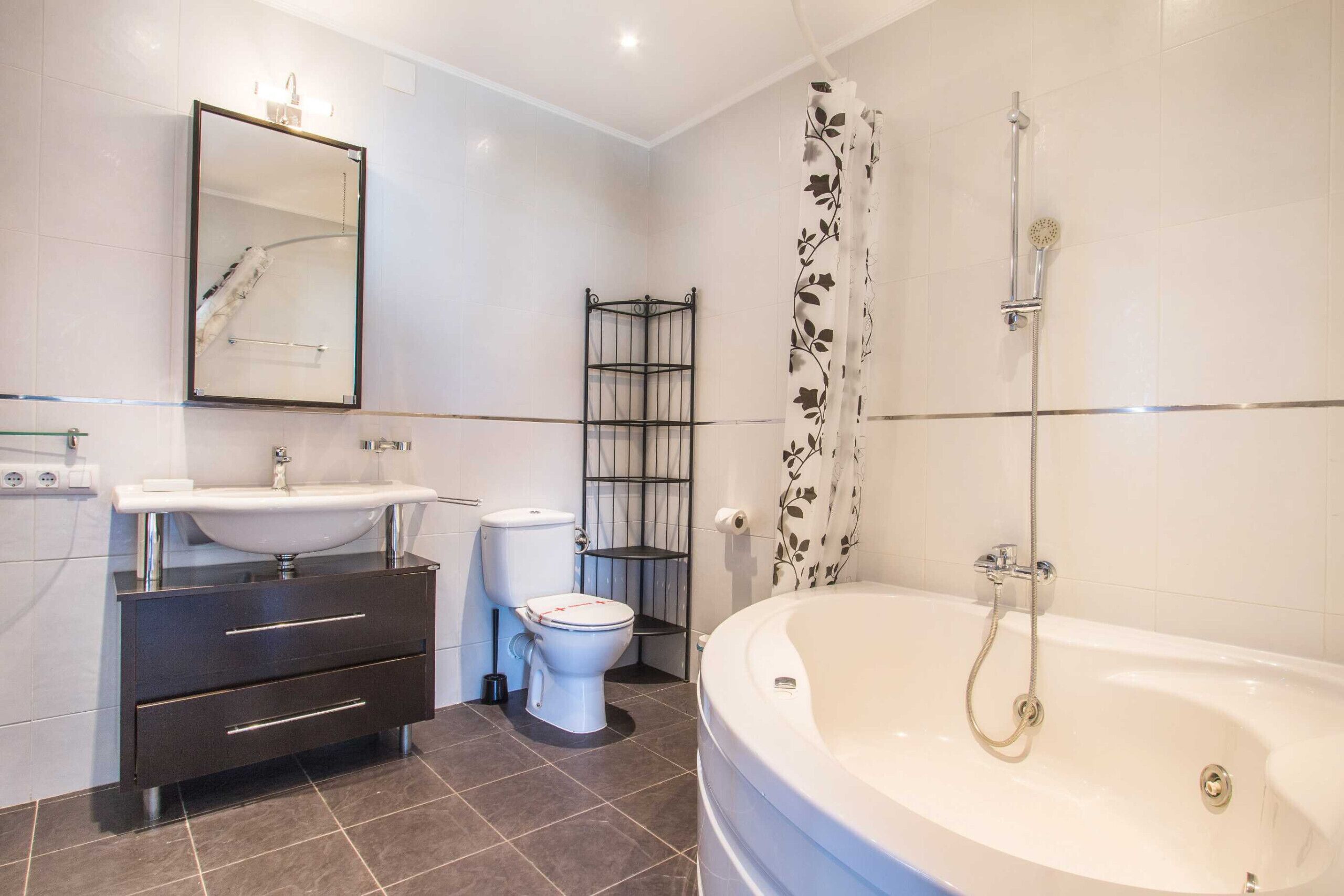 A modern bathroom with a bathtub, toilet, sink, and a mirror.