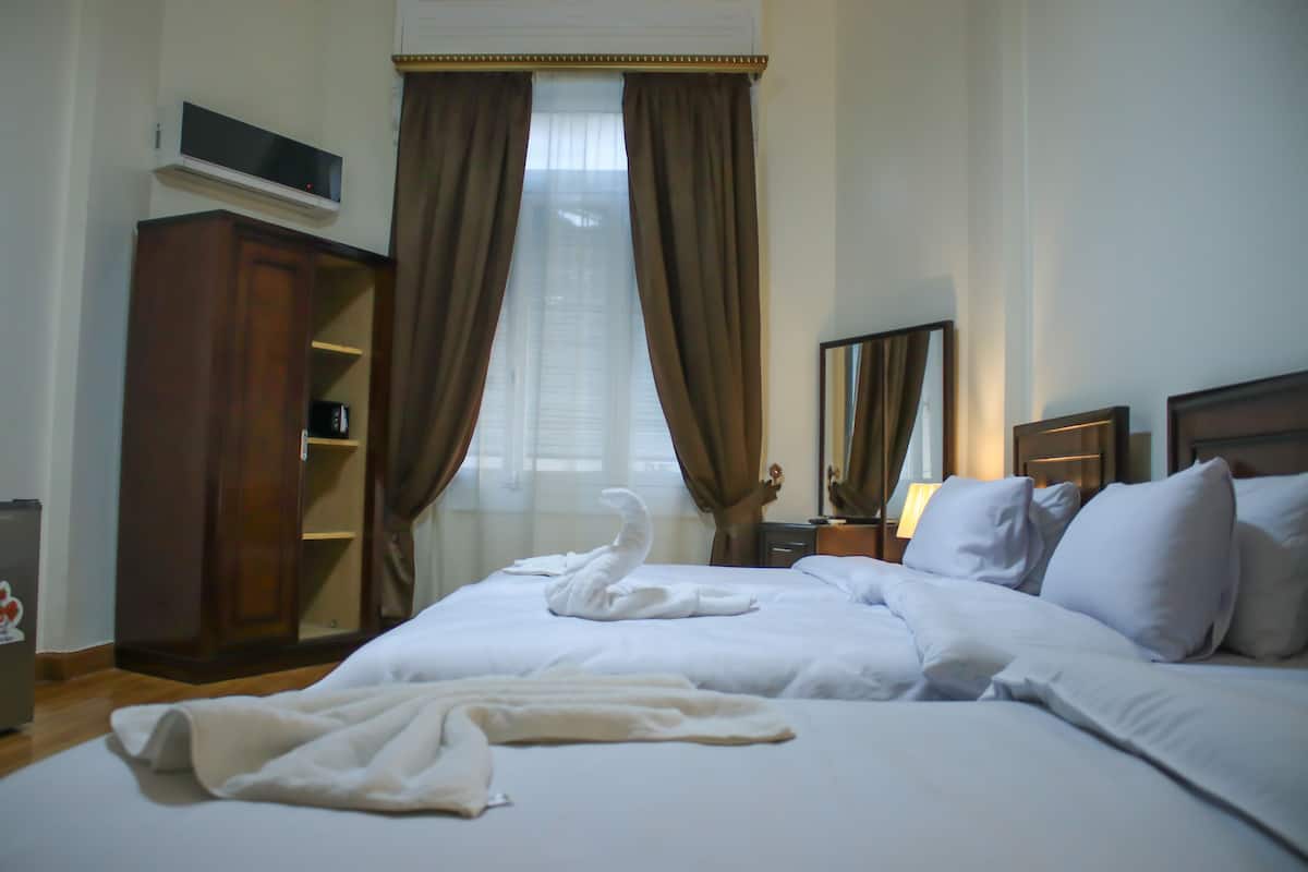 A hotel room with a large bed, a wardrobe, a flat-screen TV, and a window with curtains.