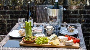 A table with a variety of cheeses, grapes, tomatoes, and a bottle of champagne. - Downclose Piggeries, North Perrott , Dorset (North Perrott)