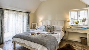 A bedroom with a bed, bedside tables, a dresser, a mirror, and a window with curtains. - Downclose Piggeries, North Perrott , Dorset (North Perrott)