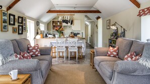 A cozy living room with a sofa, coffee table, and a dining area with chairs and a table. - Downclose Piggeries, North Perrott , Dorset (North Perrott)