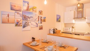 Una cocina moderna con armarios blancos, encimera de madera y una mesa de comedor para cuatro personas.