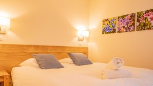 Una cama bien hecha con almohadas, una toalla enrollada y luces empotradas.