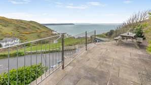 A stone staircase leading to a viewing platform with a metal railing, overlooking a coastal landscape with a body of water and a distant landmass. - 2 Bed in Mortehoe (oc-combe) (Mortehoe)