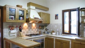 Una cocina con armarios de madera, una estufa a gas, un lavamanos y una ventana con vistas.