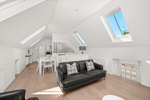 Un moderno loft con comedor, cocina y sala de estar, que incluye un sofá de cuero negro y una chimenea.