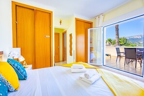 A hotel room with a bed, a nightstand, a lamp, and a view of the outdoor patio.