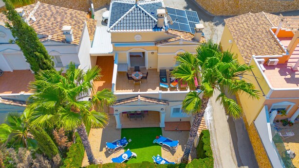 Un edificio de varios pisos con terraza en la azotea, piscina y palmeras.