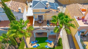 A multi-story building with a rooftop terrace, a swimming pool, and palm trees.
