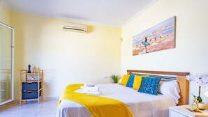 Habitación de hotel con cama, un cuadro en la pared, una mesita de noche y una ventana.