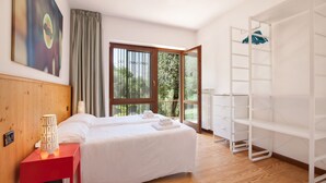 A hotel room with a bed, a red nightstand, a white wardrobe, and a view of greenery through the window. - Villa Carducci with lake view (Torri del Benaco)