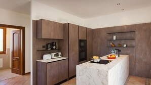 A modern kitchen with built-in appliances, a marble countertop, and wooden cabinetry. - Villa Carducci with lake view (Torri del Benaco)