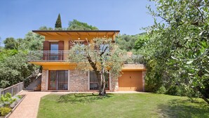A two-story house with a stone facade, a balcony, and a well-maintained lawn. - Villa Carducci with lake view (Torri del Benaco)