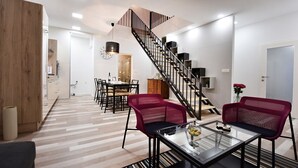 A modern living room with a staircase, a dining area, and a kitchen in the background. - Apartment Tivoli Park, Ljubljana (Ljubljana)