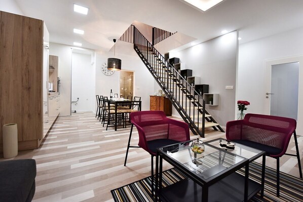 A modern living room with a staircase, a dining area, and a kitchen in the background. - Apartment Tivoli Park, Ljubljana (Ljubljana)