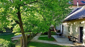 A courtyard with a tree, benches, and a building with a tiled roof. - Apartment Tivoli Park, Ljubljana (Ljubljana)