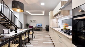A modern kitchen with a dining area, a staircase, and a TV in the background. - Apartment Tivoli Park, Ljubljana (Ljubljana)