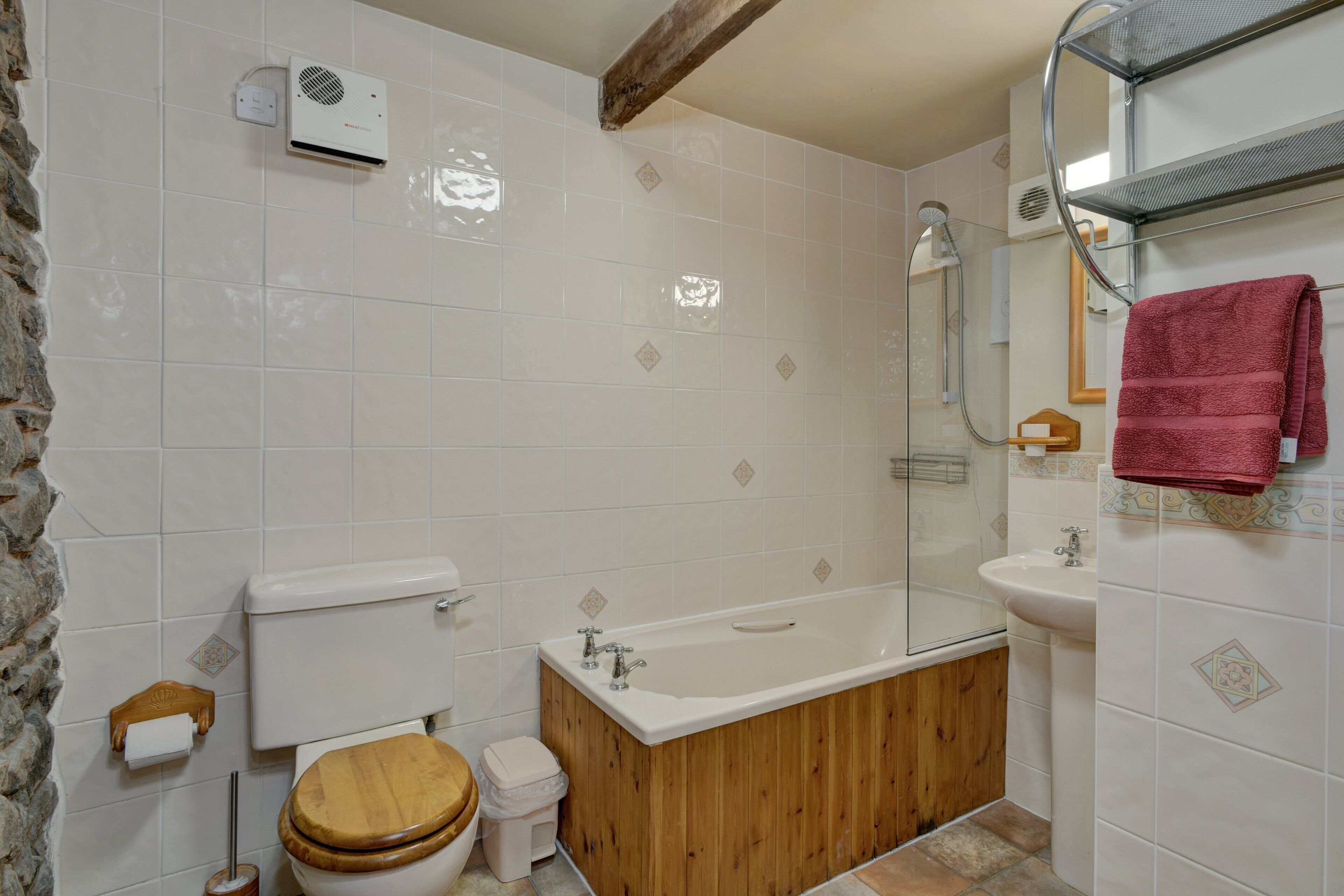 Een badkamer met een houten bad, toilet, wastafel en douche.
