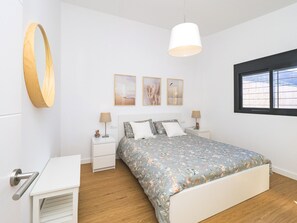 Une chambre à coucher avec un lit, des tables de chevet, un luminaire suspendu et une fenêtre donnant sur un paysage agréable.