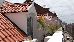 Una terraza con techo de baldosas, una mesa con dos sillas y una planta en maceta.
