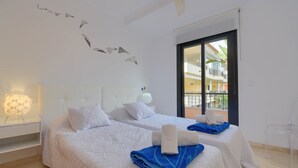 A hotel room with two beds, a nightstand, a lamp, and a view of the outside balcony. - Jardines del Pla - Javea, Costa Blanca (Javea)
