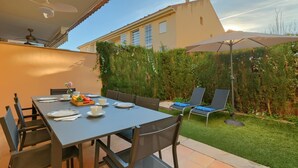 An outdoor dining area with a table set for four, surrounded by chairs, and a large umbrella providing shade. - Jardines del Pla - Javea, Costa Blanca (Javea)