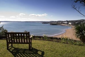 Un banc placé face à une plage, offrant une vue dégagée sur la mer et les bâtiments situés au loin.