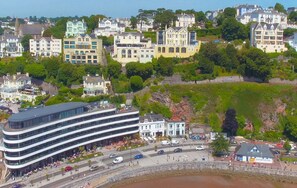 Une ville côtière où se côtoient des bâtiments modernes et historiques, un hôtel moderne à l’architecture originale et une côte rocheuse.