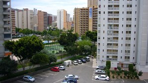 A high-rise residential building with multiple balconies, a parking lot, and surrounding greenery. - PARAISO ESPERANTO (1 BEDROOM) (Benidorm)