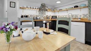 Una cocina moderna con una mesa de madera, sillas, un jarrón de flores y diversos electrodomésticos.