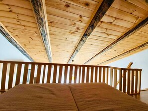 Relax in a cozy loft-style space with a sloped ceiling and balcony access.