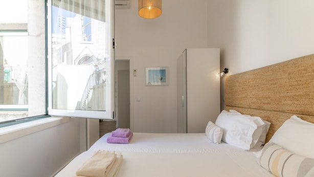 Une chambre d’hôtel avec un lit, une fenêtre, une armoire et un tableau au mur.