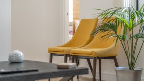 Une pièce avec deux chaises jaunes, une plante en pot et une petite table sur laquelle se trouve un objet décoratif.