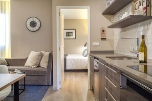 A compact living space with a kitchenette, a dining area, and a bedroom.