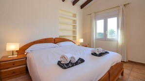 A neatly made bed with white linens, a wooden headboard, and two bedside tables with lamps.