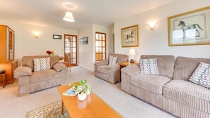 A living room with striped sofas, a wooden coffee table, and a door leading to another room. - 1 Bed in Ilfracombe (oc-n2052) (Berrynarbor)