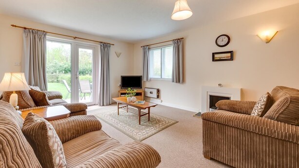A living room with two sofas, a coffee table, a TV, and a fireplace. - 1 Bed in Ilfracombe (oc-n2052) (Berrynarbor)