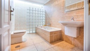 Une salle de bain moderne équipée de toilettes, d’une baignoire et d’un lavabo.