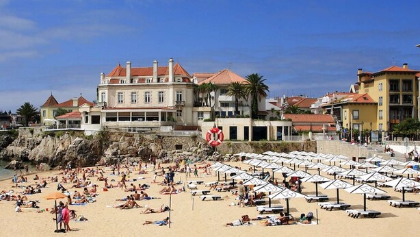 Ein Strand mit vielen Sonnenschirmen und Menschen, die sich sonnen.
