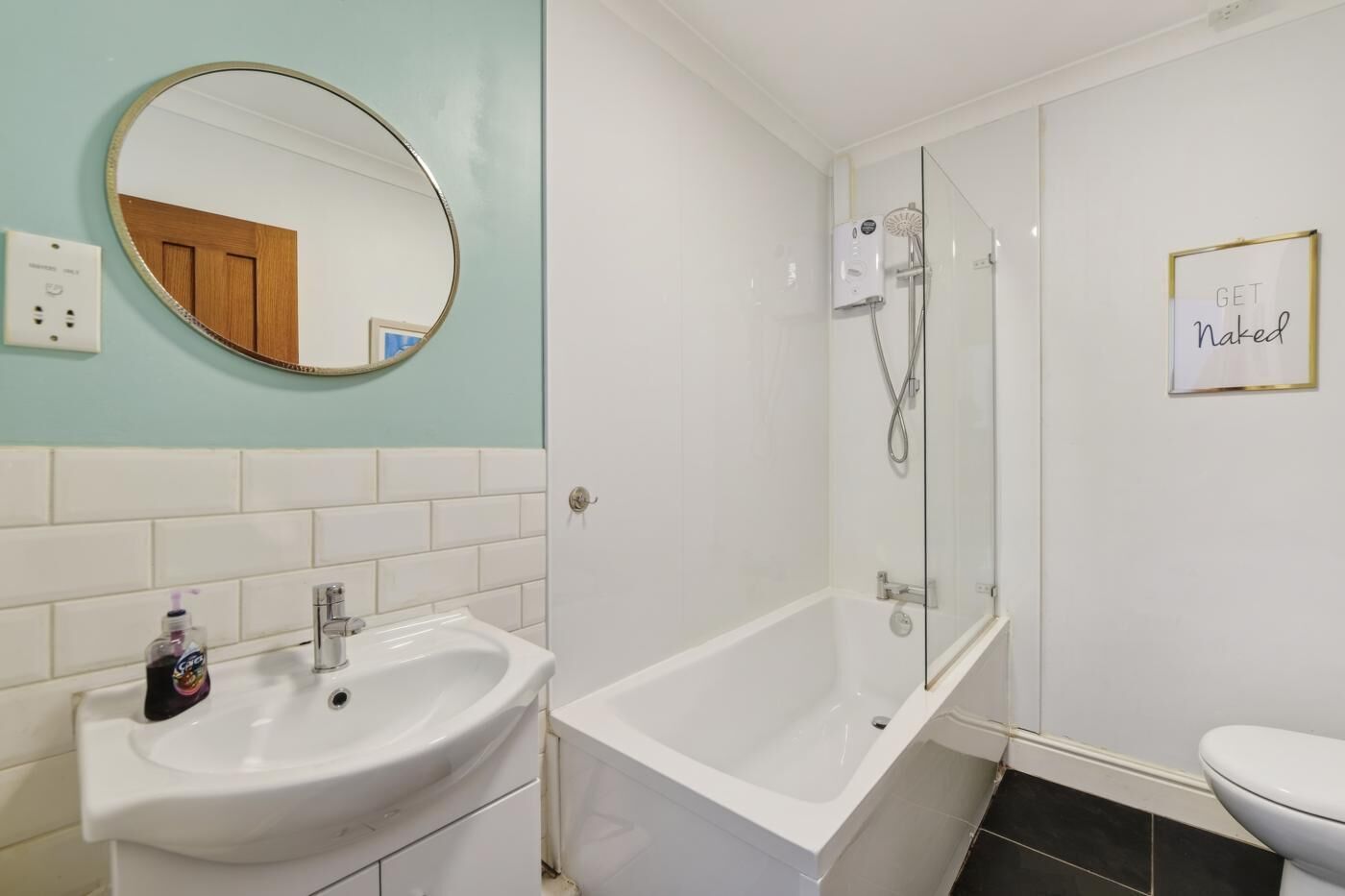 A bathroom with a sink, mirror, shower, and toilet.