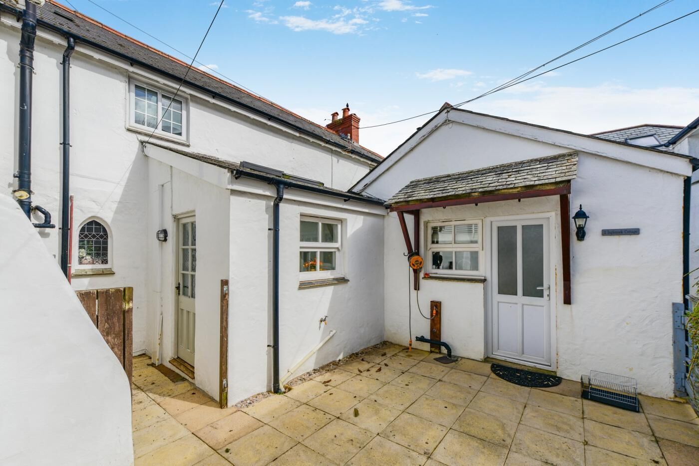 A white building with a tiled patio, a wooden door, and a small window.