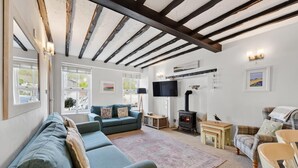 A cozy living room with a sofa, a television, a fireplace, and a window with a view.