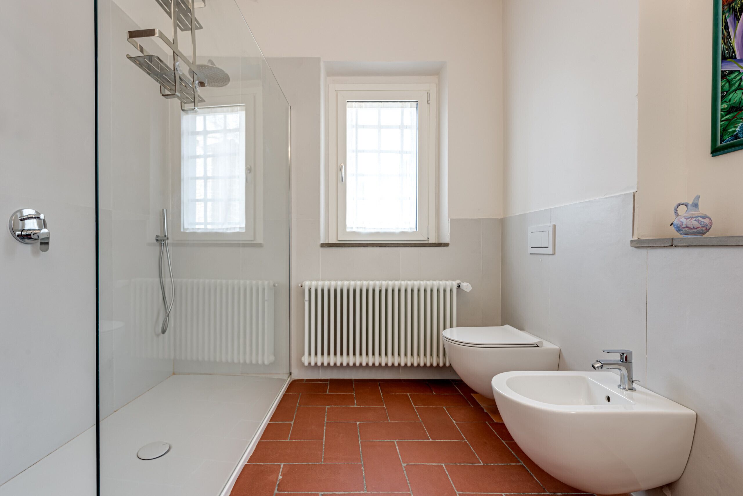 Une salle de bain équipée d’une douche, de toilettes, d’un bidet et d’un radiateur.